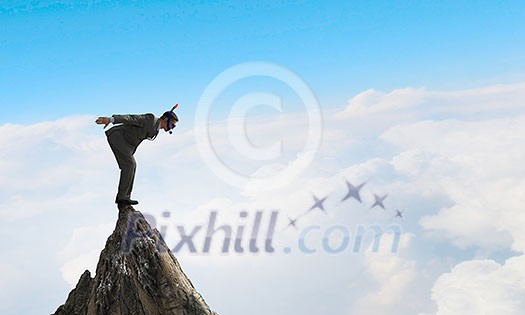 Man wearing suit and diving mask jumping from rock top. Mixed media . Mixed media Man wearing suit and diving mask jumping from rock top. Mixed media . Mixed media