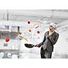 Young elegant businesswoman in suit and cook hat with pan in hands. Mixed media