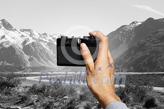 Photographer holding retro camera and taking photos of natural landscape Photographer holding retro camera and taking photos of natural landscape