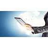 Businesswoman holding tablet computer against blue background. Mixed media