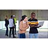 young multiethnic team of business people in group, architect and engineer on construction site checking documents and business workflow using laptop and tablet computer in new startup office