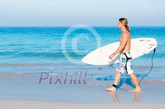 A young surfer with his board on the beach