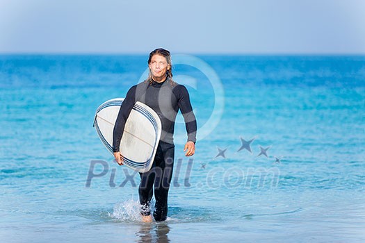 A young surfer with his board on the beach