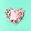 Congratulation card with floral heart from roses and craft envelope on a light turquoise background, place for text. Top view.