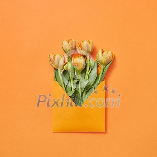Spring fresh flowers tulips in craft envelope on a yellow background with copy space. Love letter for congratulation. Flat lay Spring fresh flowers tulips in craft envelope on a yellow background with copy space. Love letter for congratulation. Flat lay