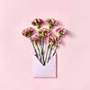 Handmade blank envelope with bouquet of carnations flowers on a pastel pink background, copy space. Top view. Congratulation card.