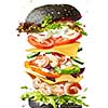 Homemade delicious sandwich of flying ingredients shrimp, fresh organic vegetables and black bun on a white background with copy space.