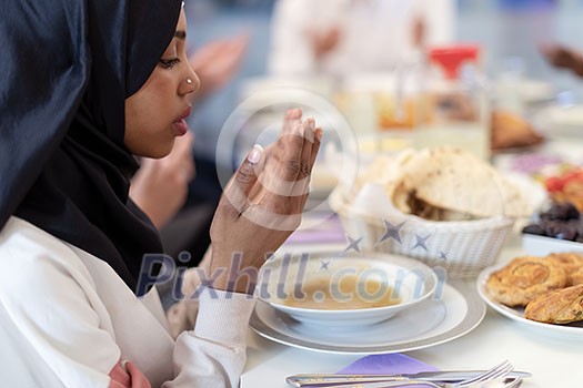 modern black muslim woman praying before having iftar dinner together with multiethnic family during a ramadan feast at home modern black muslim woman praying before having iftar dinner together with multiethnic family during a ramadan feast at home