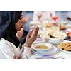 modern black muslim woman praying before having iftar dinner together with multiethnic family during a ramadan feast at home