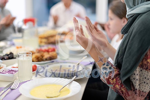 modern muslim family praying before having iftar dinner together during a ramadan feast at home modern muslim family praying before having iftar dinner together during a ramadan feast at home