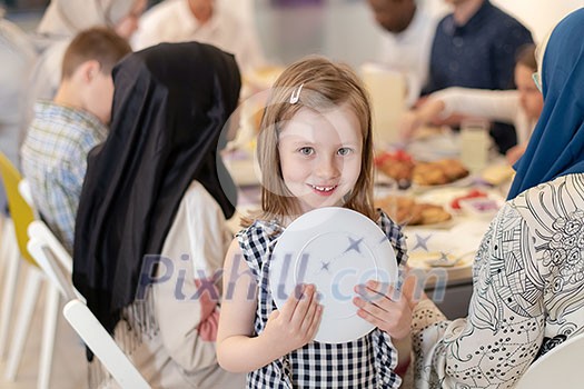cute little girl enjoying iftar dinner together with modern multiethnic muslim family in the background during a ramadan feast at home cute little girl enjoying iftar dinner together with modern multiethnic muslim family in the background during a ramadan feast at home