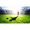 Little soccer champion on green field and his shadow on grass. Mixed media
