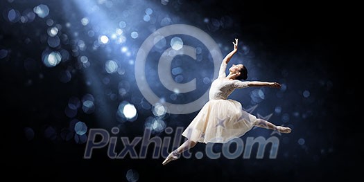 Elegant woman dancer in white dress against dark background Elegant woman dancer in white dress against dark background
