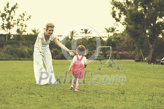Young Mother and cute little daughter enjoying free time playing outside at backyard on the grass, happy family in nature concept Young Mother and cute little daughter enjoying free time playing outside at backyard on the grass, happy family in nature concept