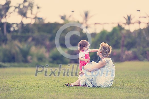 Young Mother and cute little daughter enjoying free time playing outside at backyard on the grass, happy family in nature concept Young Mother and cute little daughter enjoying free time playing outside at backyard on the grass, happy family in nature concept