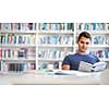 Students in a library - handsome student reading a book for his class in a bright modern library
