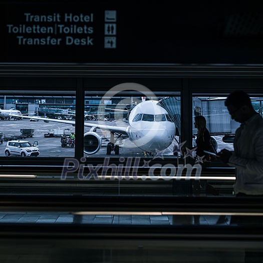 Airport rush: people with their suitcases walking along a corridor (motion blurred image; color toned image) Airport rush: people with their suitcases walking along a corridor (motion blurred image; color toned image)