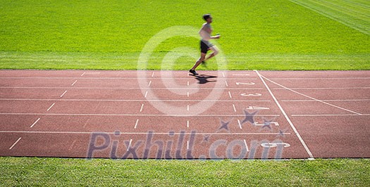 Runner on a running track finishing a race first (motion blurred image) Runner on a running track finishing a race first (motion blurred image)