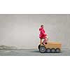 Little girl playing with cardboard train on concrete wall background