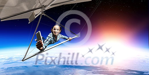 Selfie shot of brave hang glider pilot soaring with book in hands. Mixed media Selfie shot of brave hang glider pilot soaring with book in hands. Mixed media