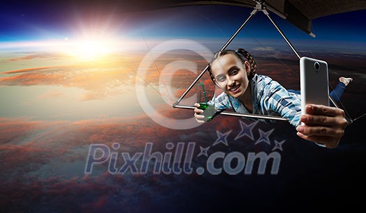 Selfie shot of brave hang glider pilot soaring with book in hands. Mixed media Selfie shot of brave hang glider pilot soaring with book in hands. Mixed media