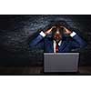 Handsome afroamerican businessman sitting at desk and working on laptop. Mixed media