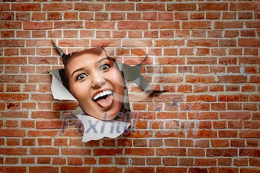 Face of young curious woman peeking through a hole in torn paper. Mixed media Face of young curious woman peeking through a hole in torn paper. Mixed media
