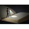 Woman with flashlight standing on pages of huge book. Mixed media