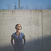 Pretty, young woman with headphones standing against concrete wall, enjoyig the hi-fi quality sound, listening to her favorite songs (color toned image)