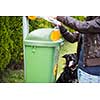 Do not let your dog foul! - Young woman grabbing a plastic bag in a park to tidy up after her dog later