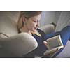 Cute young woman reading a book in a designer chair - color toned image, shallow DOF
