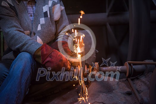 the blacksmith polishing metal products making sparks while using a grinding machine in his traditional workshop the blacksmith polishing metal products making sparks while using a grinding machine in his traditional workshop
