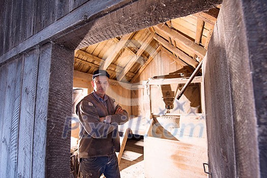 portrait of a miller in retro wooden watermill with old equipment portrait of a miller in retro wooden watermill with old equipment
