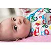 happy beautiful newborn baby boy lying on colorful blankets while playing first games at home
