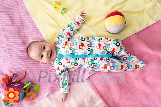 top view of happy beautiful newborn baby boy lying on colorful blankets while playing first games at home top view of happy beautiful newborn baby boy lying on colorful blankets while playing first games at home