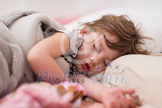 Sweet little girl covered with a blanket sleeping in bed at home Sweet little girl covered with a blanket sleeping in bed at home