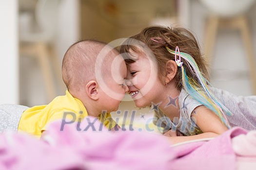 happy family little sister and her baby brother lying while playing on the floor covered with blankets at home happy family little sister and her baby brother lying while playing on the floor covered with blankets at home