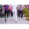 trainer training motivated active healthy senior people to performing exercise in the park