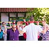 trainer training motivated active healthy senior people to performing exercise in the park