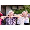 healthy senior woman exercising with friends in front of retirement home