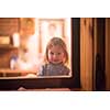 outside view of happy little cute girl playing near the window during winter time at home