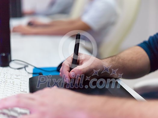 Closeup of Graphic Designer Working at Workplace. Guy Sitting at Table Retouching Photo Using Digital Tablet with Pen and desktop computer Indoors. Freelancing and Distance Job Concept Closeup of Graphic Designer Working at Workplace. Guy Sitting at Table Retouching Photo Using Digital Tablet with Pen and desktop computer Indoors. Freelancing and Distance Job Concept