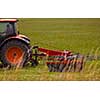 Man driving tractor with large wheels during harvest in the field