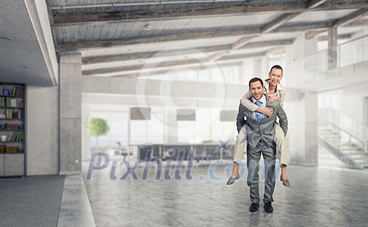 Businesswoman riding on back of her colleague in modern office Businesswoman riding on back of her colleague in modern office