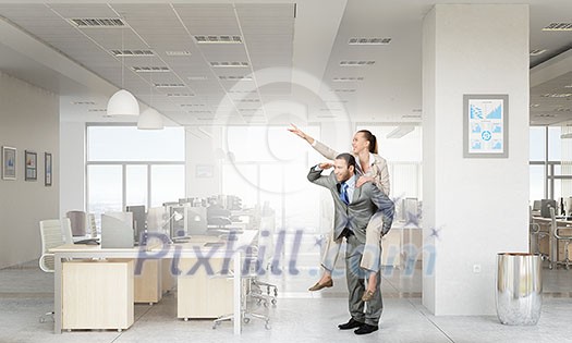 Businesswoman riding on back of her colleague in modern office Businesswoman riding on back of her colleague in modern office