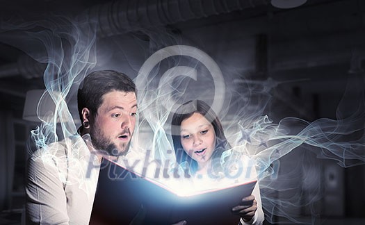Young father and daughter read book and light coming out of pages Young father and daughter read book and light coming out of pages