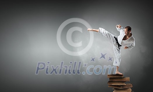 Determined karate man on pile of old books Determined karate man on pile of old books