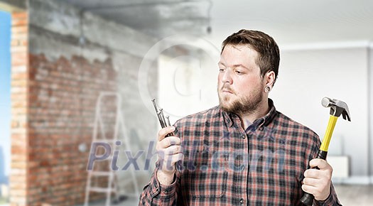 Casual man in checked shirt indoors with hammer and nails Casual man in checked shirt indoors with hammer and nails