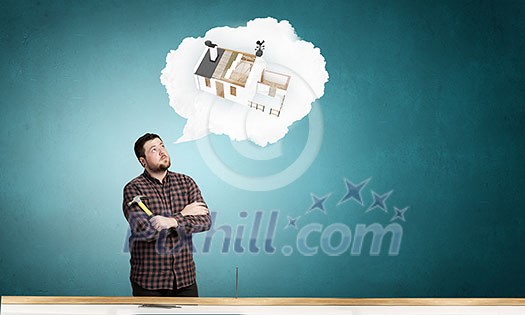 Casual man in checked shirt indoors with hammer and nails