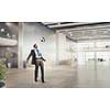 Businessman in suit in modern office jumping to hit soccer ball